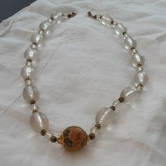 Vintage unbranded clear lucite oval beaded necklace w/central floral bead.