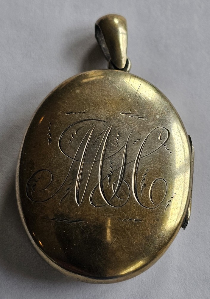 Antique gold tone oval locket with etched intricate script monogram and bail