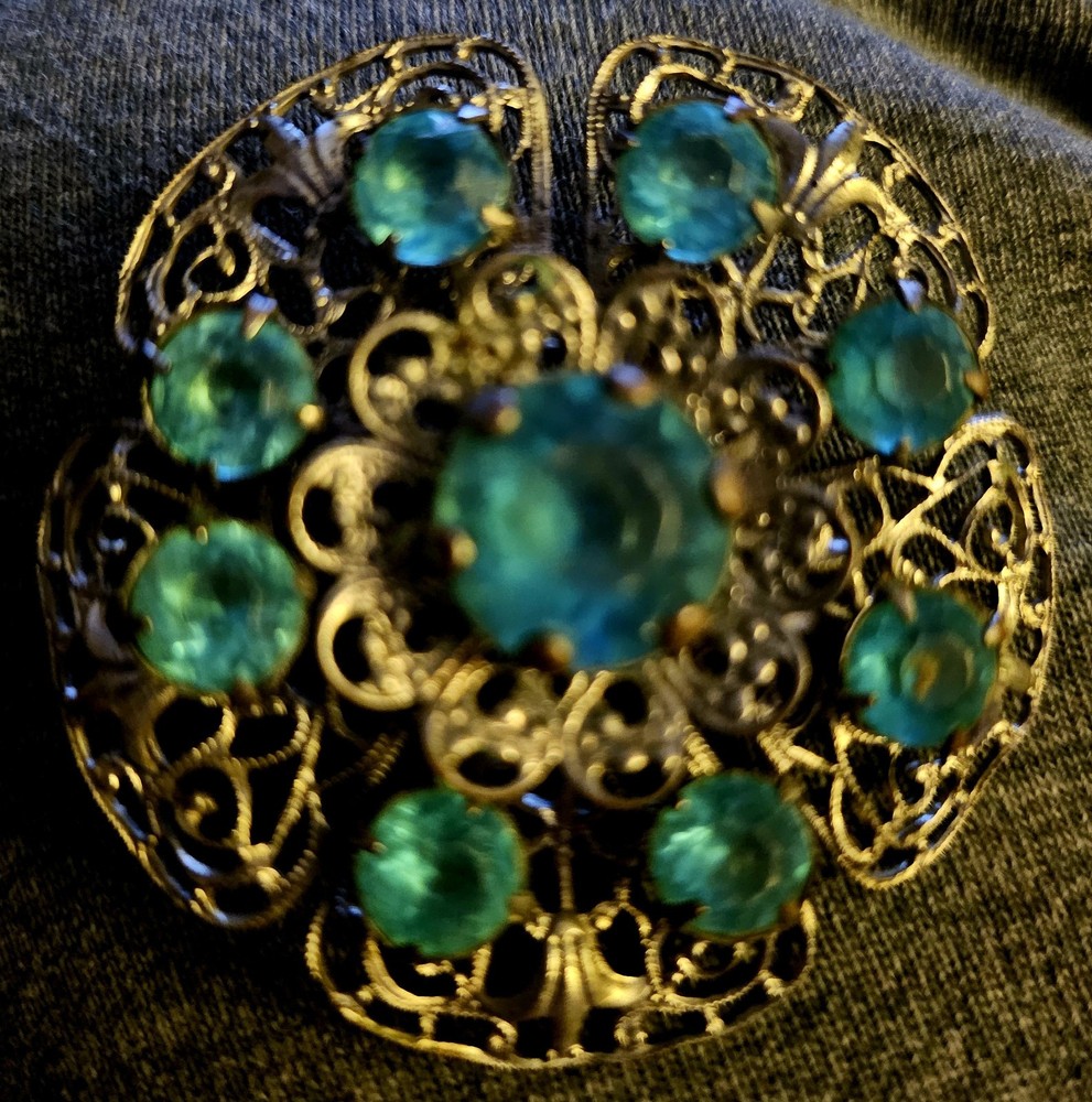 VTG Brooch featuring blue rhinestones set in a silver-tone filigree metal.