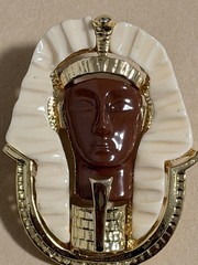 Egyptian Revival King Tut brooch featuring gold metal, white lucite, red resin
