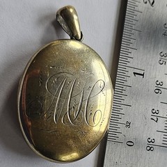 Antique gold tone oval locket with etched intricate script monogram and bail