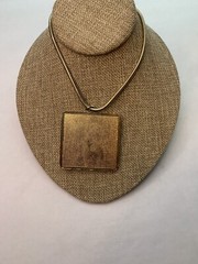 Large gold tone snake chain there’s a large square black suede pendant￼
