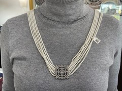 White multi-strand pearl necklace features a detailed rhinestone-set clasp