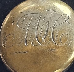 Antique gold tone oval locket with etched intricate script monogram and bail