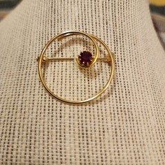 Gold Tone Swirl Circle Brooch With Red Rhinestone Accent.