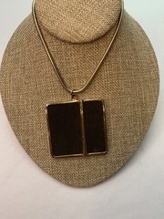Large gold tone snake chain there’s a large square black suede pendant￼