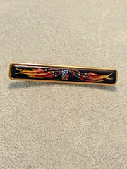vintage Hermes enamel bar brooch featuring a vibrant red, blue, and gold JB1