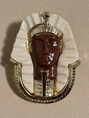 Egyptian Revival King Tut brooch featuring gold metal, white lucite, red resin