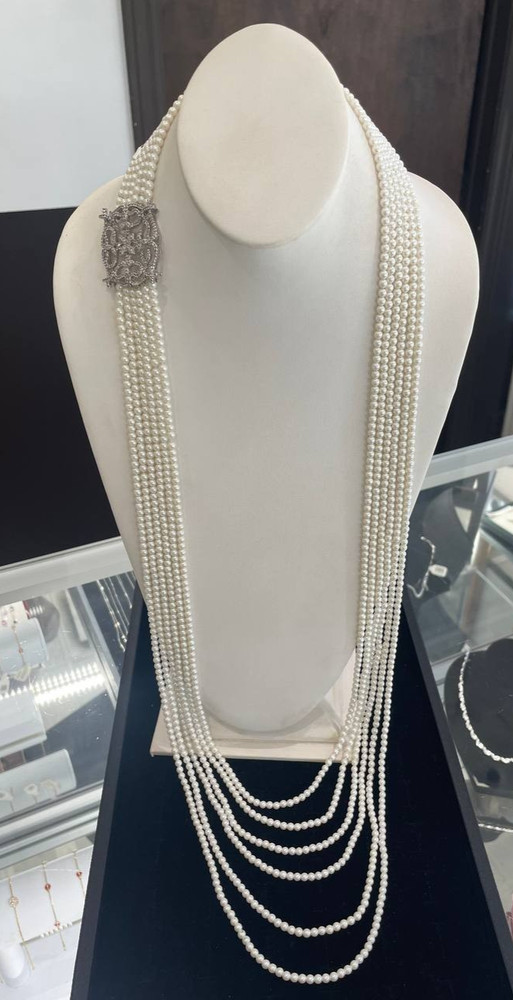 White multi-strand pearl necklace features a detailed rhinestone-set clasp