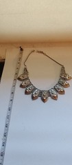 Bohemian design necklace with curved row of repeating leaf-or shield- shape pane